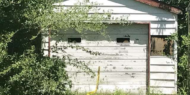 Trees grow in front of the entrance of a garage Tuesday, June 6, 2017, where the remains of a 7-year-old child was found in Centreville, Ill. A Las Vegas woman told investigators Tuesday that her dead child had been in a southern Illinois home for two years, and authorities later found human remains in the vacant house, according to authorities. Centreville police Sgt. DeMarius Thomas Sr. told the St. Louis Post-Disaptch that police believe the child was killed in nearby Belleville, Ill, and dumped in the garage. (Christine Byers/St. Louis Post-Dispatch via AP)