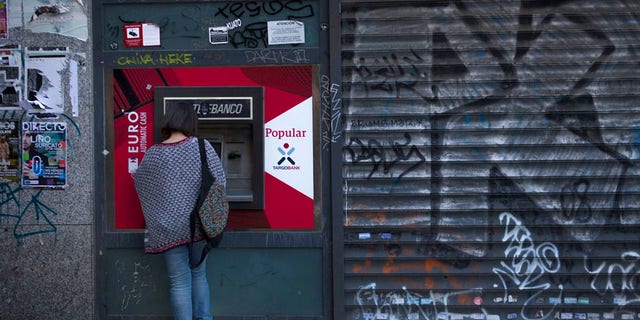 A woman uses a Banco Popular's ATM in Madrid, Wednesday, June 7, 2017. Spain's Banco Santander has acquired Banco Popular, the troubled lender that lost more than half of its shares value over the past week. (AP Photo/Francisco Seco)
