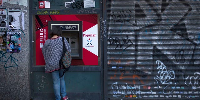 A woman uses a Banco Popular's ATM in Madrid, Wednesday, June 7, 2017. Spain's Banco Santander has acquired Banco Popular, the troubled lender that lost more than half of its shares value over the past week. (AP Photo/Francisco Seco)