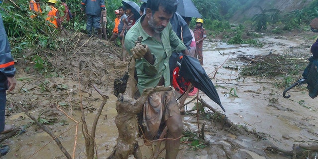 A man carries the carcass of a goat as rescuers search amid the mud after a landslide in Bandarban, Bangladesh, Tuesday, June 13, 2017. Heavy rains triggered landslides that killed dozens in southeast Bangladesh, officials said Tuesday, as police and soldiers struggled to reach the remote districts with aid. (AP Photo)