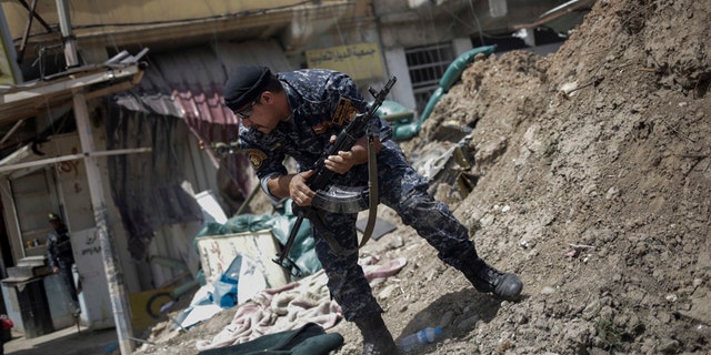 In this April 29, 2017 file photo, an Iraqi Federal Policeman runs away after he fired shots at an Islamic State group position on the western side of Mosul, Iraq.