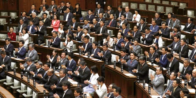 Upper house members of the ruling coalition clap their hands after parliament approved a contentious bill that makes it a crime to plan a crime, in Tokyo Thursday, June 15, 2017. The ruling coalition pushed the conspiracy legislation through the upper house, bypassing committee approval that normally precedes a vote by the full house. (Kyodo News via AP)