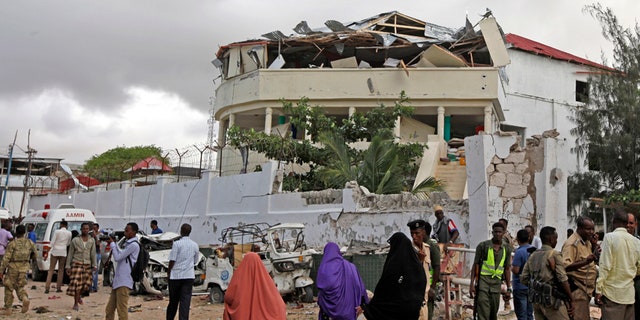 Somalis gather outside a destroyed building near a restaurant that was the scene of a car bomb blast and gun battle in Mogadishu, Somalia Thursday, June 15, 2017.
