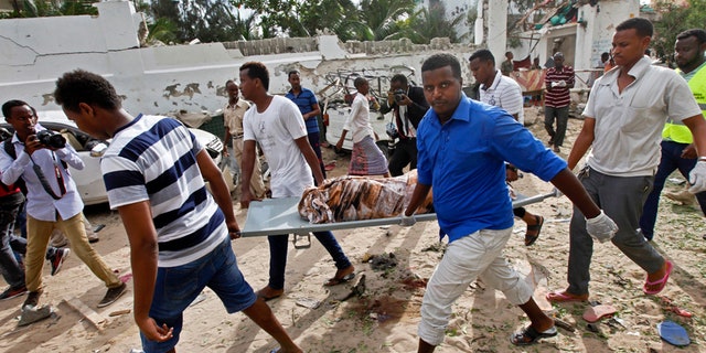 Somali men carry away the body of a civilian who was killed in a militant attack on a restaurant in Mogadishu, Somalia Thursday, June 15, 2017.