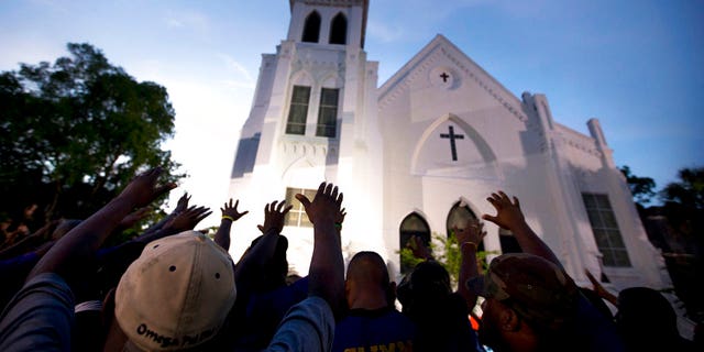 The men of Omega Psi Phi fraternity lead a crowd of people in prayer outside the Emanuel AME Church, after a memorial for the nine people killed by Dylann Roof in Charleston, S.C. June 17, 2017. (AP Photo/Stephen B. Morton)