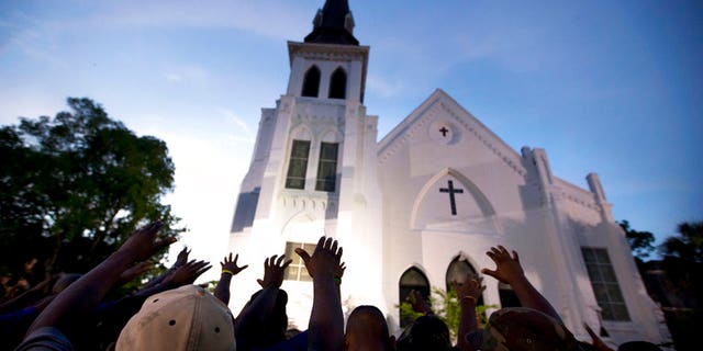 The men of Omega Psi Phi fraternity lead a crowd of people in prayer outside the Emanuel AME Church, after a memorial for the nine people killed by Dylann Roof in Charleston, S.C. June 17, 2017. (AP Photo/Stephen B. Morton)