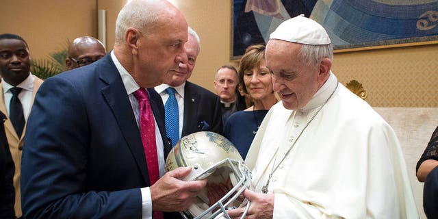 Pope Francis is presented with a Pro Football Hall of Fame helmet by an unidentified member of an NFL Hall of Fame delegation during a private audience at the Vatican, Wednesday, June 21, 2017. (L'Osservatore Romano/Pool Photo via AP)