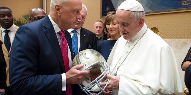 Pope Francis is presented with a Pro Football Hall of Fame helmet by an unidentified member of an NFL Hall of Fame delegation during a private audience at the Vatican, Wednesday, June 21, 2017. (L'Osservatore Romano/Pool Photo via AP)