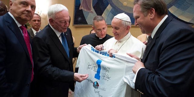 Pope Francis is presented with a Pro Football Hall of Fame jersey bearing his name by Dallas Cowboys owner Jerry Jones, second from left, during a private audience with an NFL Hall of Fame delegation at the Vatican, Wednesday, June 21, 2017. (L'Osservatore Romano/Pool Photo via AP)