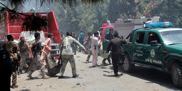 Afghans carry an injured man after a suicide car bombing in Helmand province southern of Kabul, Afghanistan, Thursday, June 22, 2017. The bomber struck outside a bank, targeting Afghan troops and government employees waiting to collect their salaries ahead of a major Muslim holiday and killing at least two dozen people, officials said. (AP Photo/Abdul Khaliq)