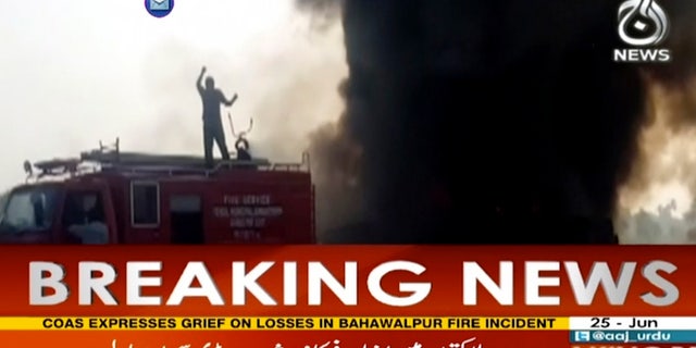 In this image taken from video, black smoke rises from oil tanker on road in Bahawalpur, Pakistan, Sunday, June 25, 2017. An overturned oil tanker burst into flames in Pakistan on Sunday, killing people who had rushed to the scene of the highway accident to gather leaking fuel, an official said. (AAJ News via AP Video)