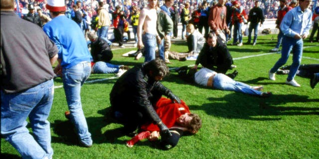 FILE - In this April 15, 1989 file photo, police, stewards and supporters tend and care for wounded supporters on the pitch at Hillsborough Stadium, in Sheffield, England. British prosecutors on Wednesday June 28, 2017, are set to announce whether they plan to lay charges in the deaths of 96 people in the Hillsborough stadium crush _ one of Britainâs worst-ever sporting disasters. (AP Photo, File)