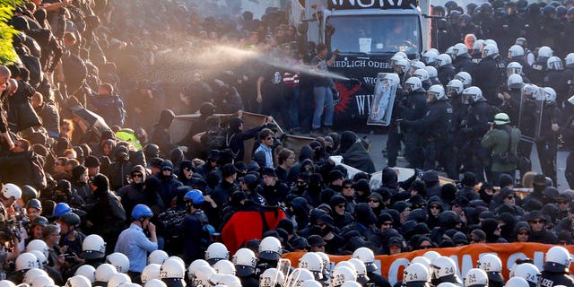 A police officer sprays a crowd of protesters with liquid in Hamburg, Germany during a protest against the G-20 summit.