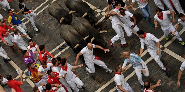 Revellers run in front of Jose Escolar fighting bulls during the second running of the bulls at the San Fermin Festival, in Pamplona, northern Spain, Saturday, July 8, 2017. Revellers from around the world flock to Pamplona every year to take part in the eight days of the running of the bulls. (AP Photo/Alvaro Barrientos)