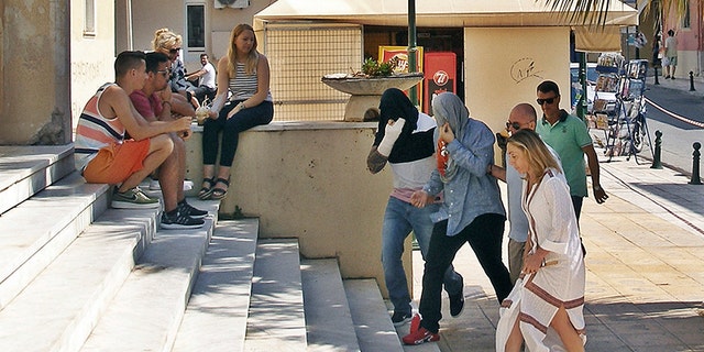 Policeman in plain clothes lead two suspects , center, as they enter the court in Zakynthos island, Greece, Tuesday, July 11, 2017.