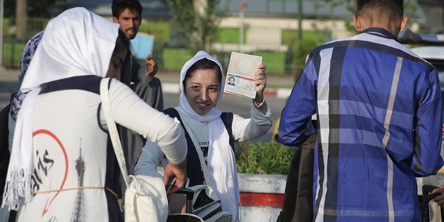 A members of a female robotics team from Herat province, shows her U.S. Visa as she leaves Kabul to the U.S. from Kabul Airport, in Kabul, Afghanistan, Friday, Jun 14, 2017. The third time's the charm for Afghanistan's all girl robotics team, who will be allowed entry into the U.S. to compete in a competition after President Donald Trump personally intervened to reverse a decision twice denying them enter into the country. (AP Photos/Massoud Hossaini)