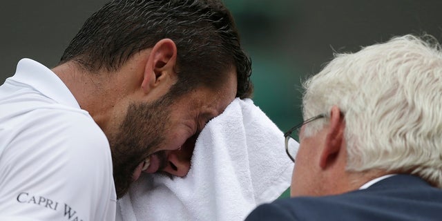 Croatia's Marin Cilic has treatment on his foot as he takes a medical timeout during the Men's Singles final match against Switzerland's Roger Federer on day thirteen at the Wimbledon Tennis Championships in London Sunday, July 16, 2017. (Daniel Leal-Olivas/Pool Photo via AP)