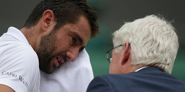Croatia's Marin Cilic wipes his face as he has treatment on his foot as he takes a medical timeout during the Men's Singles final match against Switzerland's Roger Federer.