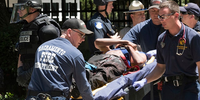 In this June 26, 2016, file photo, paramedics rush a stabbing victim to an ambulance after violence erupted during a white nationalist group's rally outside the state Capitol in Sacramento, Calif.