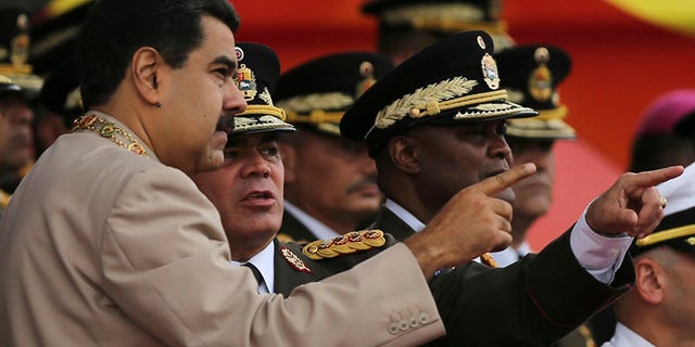 FILE - In this June 24, 2017 file photo, Venezuela's President Nicolas Maduro, left, talks to his Defense Minister Vladimir Padrino Lopez during Army Day celebrations at Fuerte Tiuna, in Caracas, Venezuela. Padrino Lopez challenged on Wednesday, July 19, 2017 the countries that have declared against the government's initiative to rewrite Venezuela's constitution, saying the nation will not submit to foreign governments. (AP Photo/Fernando Llano, File)