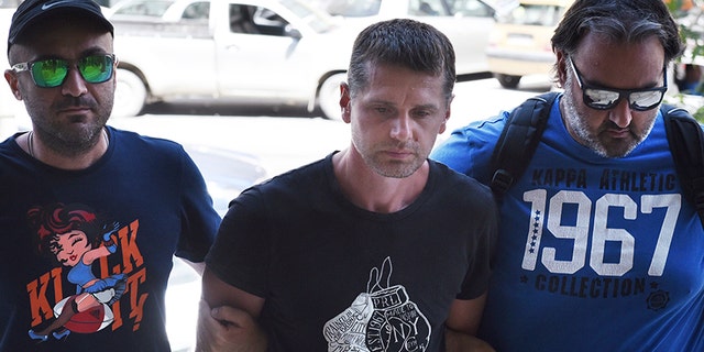 A Russian man identified as Alexander Vinnik in this photo dated Wednesday, July 26, 2017, is escorted by police officers to the courthouse at the northern Greek city of Thessaloniki.