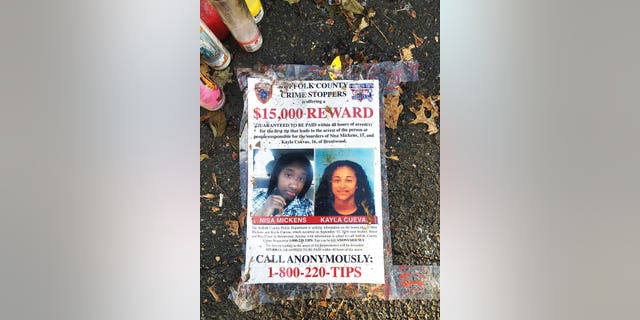 A poster featuring photos of Nisa Mickens and Kayla Cuevas is part of a memorial near the spot where their bodies were found in Brentwood, N.Y. The two girls were beaten and hacked to death by a carload of gang members who spotted them walking down the street.