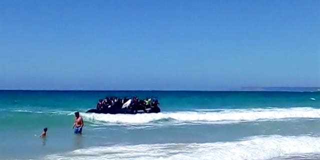 Beachgoers watched as around two dozen suspected migrants scattering on the beach in Cadiz, Spain.