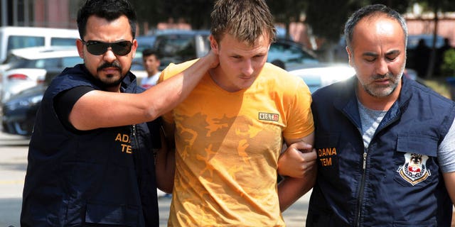 Turkish police walk with a handcuffed Renad Bakiev, center.