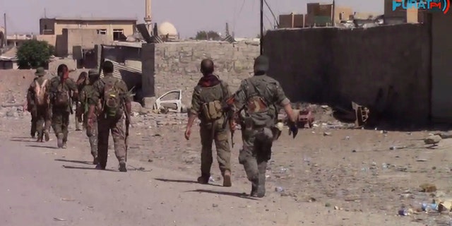 This frame grab from video released Friday, Aug. 11, 2017, and provided by Furat FM, a Syrian Kurdish activist-run media group, shows U.S.-backed Syrian Democratic Forces (SDF) fighters advance in Raqqa, Syria. U.S.-backed Syrian fighters advancing from eastern and western parts of the northern city of Raqqa have linked up for the first time in weeks after launching their offensive against Islamic State group fighters there. (Furat FM, via AP)