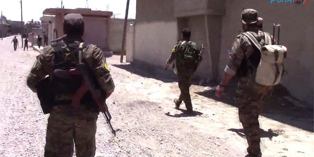 This frame grab from video released Friday, Aug. 11, 2017, and provided by Furat FM, a Syrian Kurdish activist-run media group, shows U.S.-backed Syrian Democratic Forces (SDF) fighters advance in Raqqa, Syria. U.S.-backed Syrian fighters advancing from eastern and western parts of the northern city of Raqqa have linked up for the first time in weeks after launching their offensive against Islamic State group fighters there. (Furat FM, via AP)