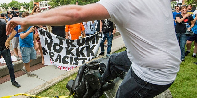 A protester kicks the toppled statue of a Confederate soldier after it was pulled down in Durham, N.C. Monday, Aug. 14, 2017.