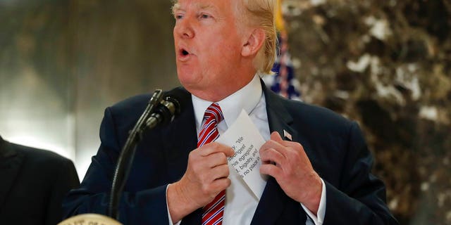President Donald Trump reaching into his suit jacket to read a quote he made on Saturday regarding the events in Charlottesville, Va., as he speaks to the media in the lobby of Trump Tower, Tuesday, Aug. 15, 2017. (AP Photo/Pablo Martinez Monsivais)