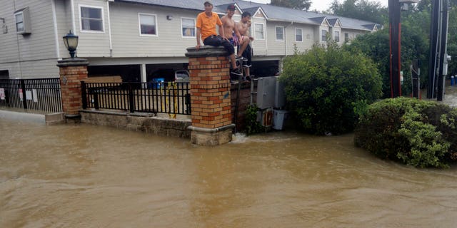 Residents sit on a fence surrounded by floodwaters in Houston, Texas.