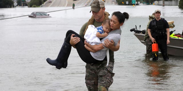 Houston Police SWAT officer Daryl Hudeck carries Catherine Pham and her 13-month-old son Aiden after rescuing them from their home surrounded by floodwaters from Tropical Storm Harvey Sunday