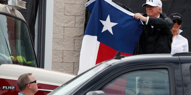 President Donald Trump holds up a Texas flag after speaking with supporters outside Firehouse 5 Tuesday, Aug. 29, 2017, following a briefing on Harvey relief efforts. (AP Photo/Evan Vucci)