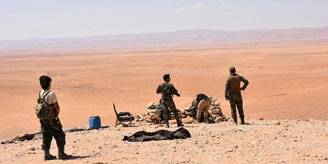 Syrian troops stand guard at one of the front line hills where they are fighting ISIS militants in the eastern city of Deir el-Zour, Syria.