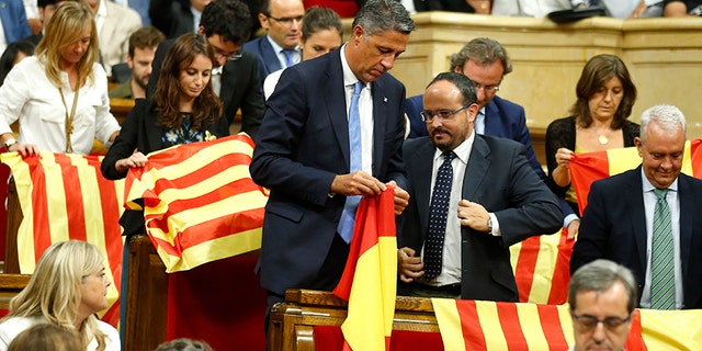 Members of the Catalan Popular Party display Spanish flags just before abandoning the session ahead of the voting, during a plenary session at the Parliament of Catalonia in Barcelona, Spain, Wednesday, Sept. 6, 2017. Catalan lawmakers are voting on a bill that will allow regional authorities to officially call an Oct. 1 referendum on a split from Spain, making concrete a years-long defiance of central authorities, who see the vote as illegal. (AP Photo/Manu Fernandez)