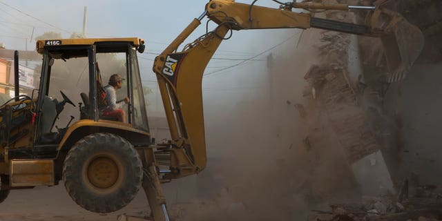 A worker hired by the owner of a candy factory warehouse demolishes the remaining parts of the building in central Juchitan, Oaxaca state, Mexico, Saturday, Sept. 9, 2017, after a magnitude 8.1 earthquake struck very late Thursday.