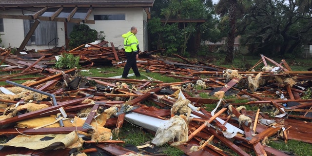 Palm Bay officer Dustin Terkoski walks over debris from a two-story home at Palm Point Subdivision in Brevard County, Fla., after a tornado touched down on Sunday, Sept. 10, 2017. (Red Huber/Orlando Sentinel via AP)