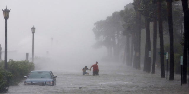 Pedestrians walk in a flooded street in Charleston on Monday, Sept. 11 during Tropical Storm Irma.
