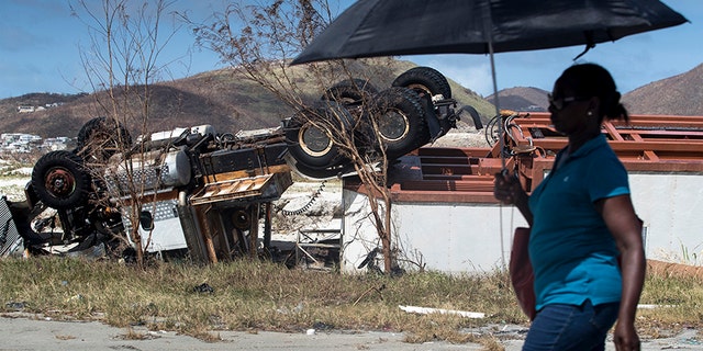 A woman passes an overturned truck after the passing of Hurricane Irma in St. Maarten.