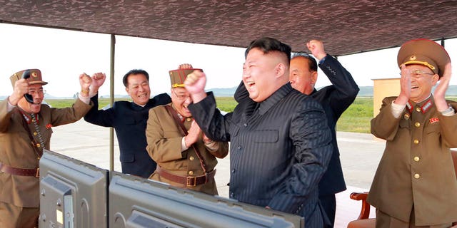 In this undated photo provided by the North Korean government, leader Kim Jong Un celebrates what is said to be the first successful test launch of an intermediate rank Hwasong-12 missile.