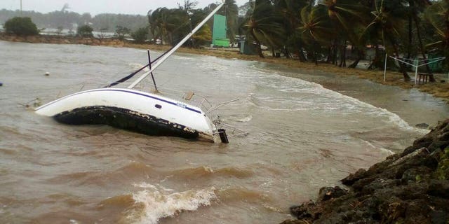 A boat lays on its side off the shore of Sainte-Anne on the French Caribbean island of Guadeloupe, early Tuesday, Sept. 19, 2017, after the passing of Hurricane Maria.