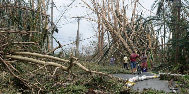 Locals help clear debris from a road after the passing of Hurricane Maria, in Yabucoa, Puerto Rico.