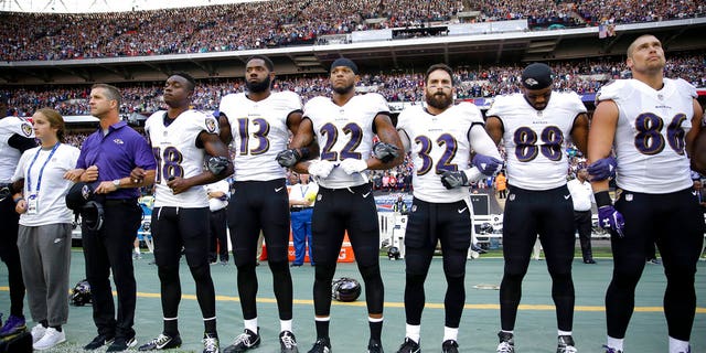 Baltimore Ravens head coach John Harbaugh stands with his arms locked with his daughter and players during the playing of the National Anthem before their game against the Jacksonville Jaguars in London.