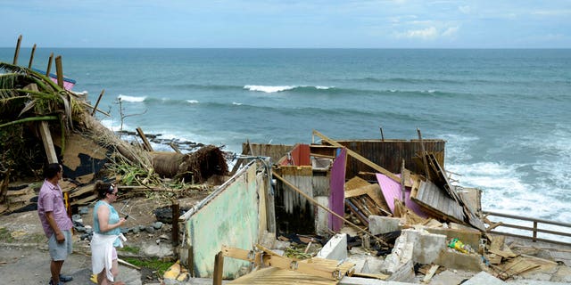 People walk by building that was destroyed in the community La Perla in Old San Juan during Hurricane Maria in San Juan, Puerto Rico, Monday, Sept. 25, 2017.