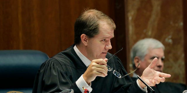 Texas Supreme Court Justice Don Willett, left, asks a question during oral arguments at the state Supreme Court in Austin, Texas. 