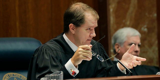 Texas Supreme Court Justice Don Willett, left, asks a question during oral arguments at the state Supreme Court in Austin, Texas.