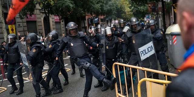 Spanish riot police removes fences thrown by people to them as they try to prevent people from reaching a voting site at a school assigned to be a polling station by the Catalan government in Barcelona, Spain, Sunday, 1 Oct. 2017. Catalan pro-referendum supporters vowed Saturday to ignore a police ultimatum to leave the schools they are occupying to use in a vote seeking independence from Spain. (AP Photo/Felipe Dana)