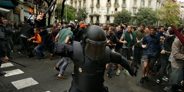FILE, In this Sunday, Oct. 1, 2017 photo, a Spanish riot police swings a club against would-be voters near a school assigned to be a polling station by the Catalan government in Barcelona, Spain, Sunday, Oct. 1, 2017. (AP Photo/Manu Fernandez, File)